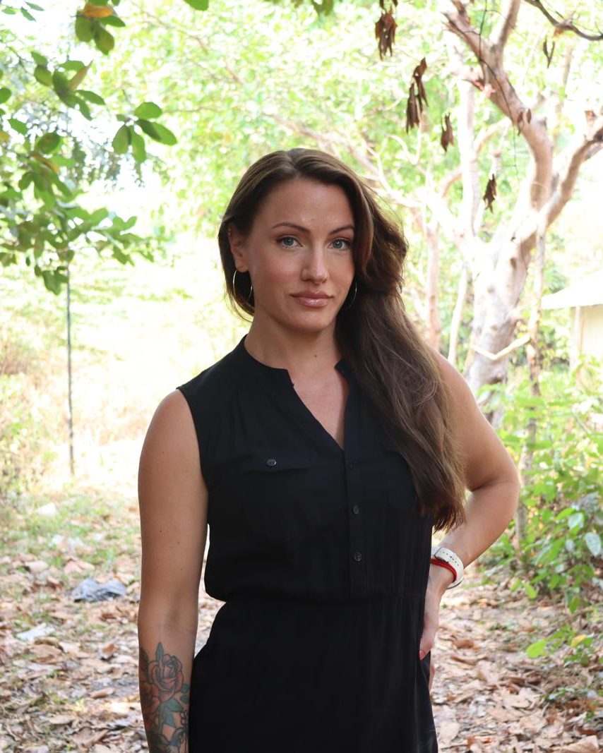 Portrait of Hilde Marie Kvaløsæter, Executive Director of EDGE Worldwide, standing among trees in Cambodia
